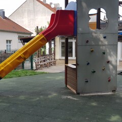 Na publicznym placu zabaw dla dzieci pod wieżą zabaw ze zjeżdżalnią, ścianką wspinaczkową i wiszącym mostem ułożono zielone maty WARCO chroniące przed upadkiem z wysokości.