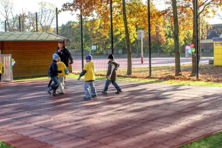 Boisko sportowe w szkole, wyposażone w czerwone płyty boiskowe WARCO, które zapewniają ochronę w razie upadku oraz precyzyjne odbicie piłki.