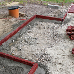 Powierzchnia małego placu zabaw jest ograniczona elastycznymi kraweznikami WARCO, które są osadzone w betonowym fundamencie.