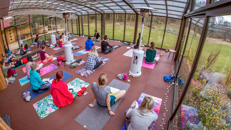 Sala do jogi z czerwonymi matami WARCO, gdzie wielu uczestników jogi rozłożyło swoje maty i wykonuje ćwiczenia.
