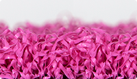 Próbka płyty WARCO z laminowaną syntetyczną trawą w kolorze różowym.