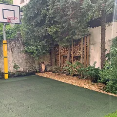 Nowe zielone boisko do koszykówki z zielonymi płytami boiskowymi WARCO, ułożone na dziedzińcu budynku mieszkalnego.