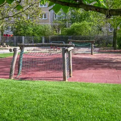 Publiczne boisko sportowe w parku miejskim z dwiema bramkami do piłki nożnej i podłogą sportową WARCO.