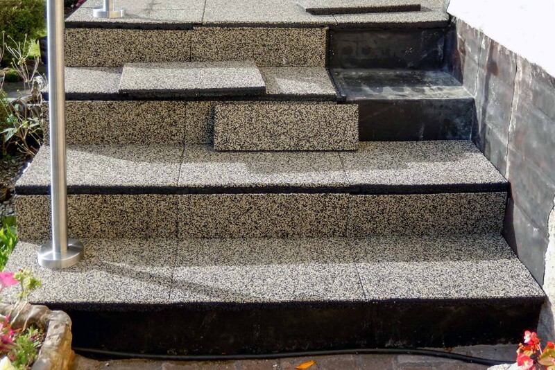 Betonowe schody prowadzące na podwyższony taras są pokrywane elastycznym pokryciem schodów WARCO w kolorze Trawertyn.
