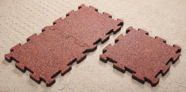 Układanie mat amortyzujących – puzzle WARCO z zamkiem formowanym na podbudowie z plastikowych kratek stabilizujących grunt.